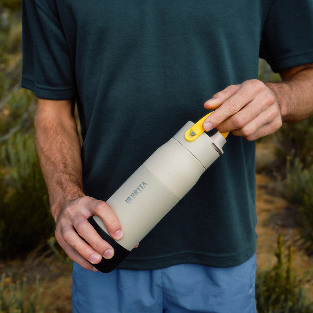 Person holding a BRITA LARQ bottle with yellow handle accessory attached to the lid