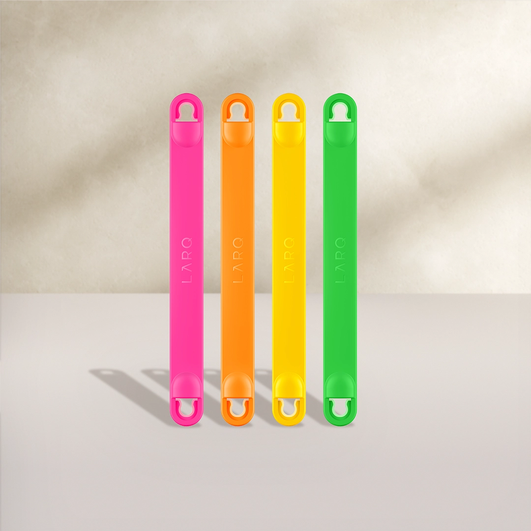 BRITA LARQ-fleshandvatten in vier kleuren: roze, oranje, geel en groen op een beige achtergrond.