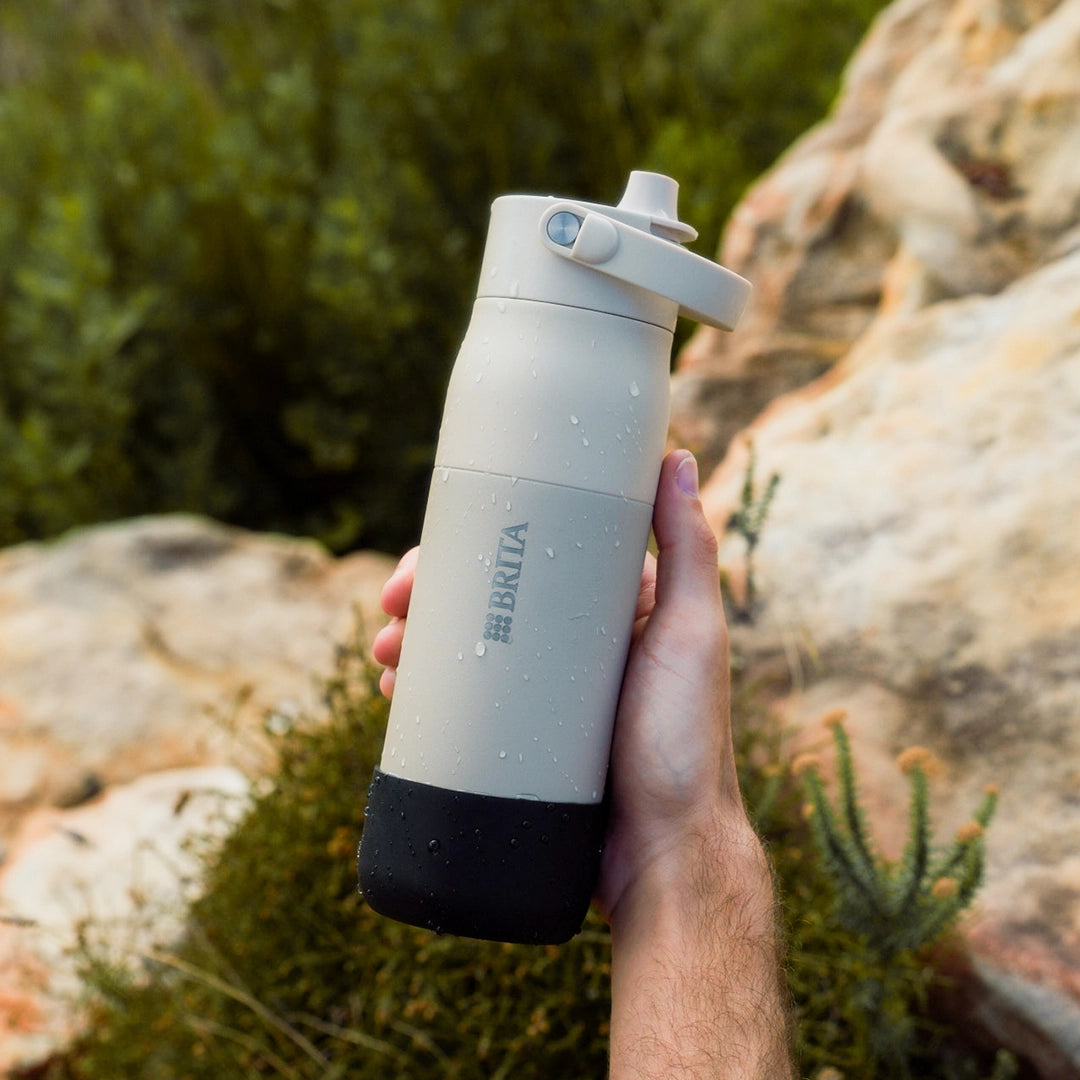 Someone holding a white BRITA LARQ water bottle with a black silicone boot in his hand.