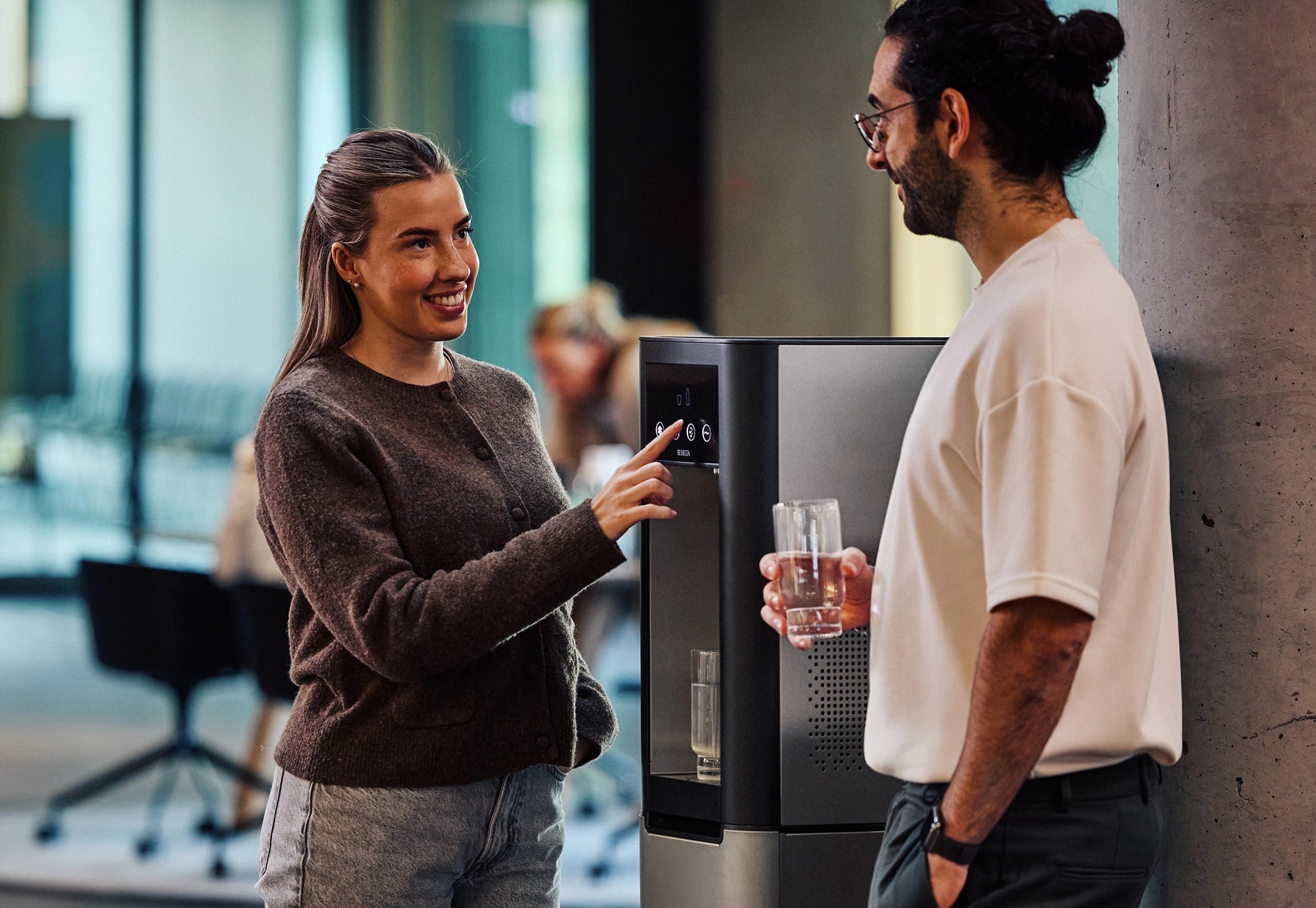 Two people using a BRITA Water Dispenser in an office environment.