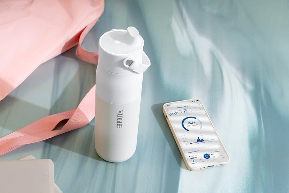 BRITA LARQ iQ Filter Bottle and smartphone with BRITA app placed on a yoga mat.