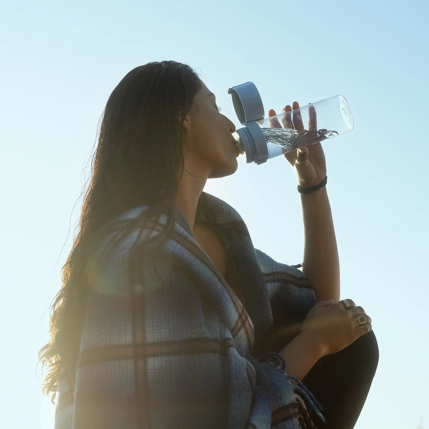 Person drinking from BRITA water filter bottle Model Vital against a clear blue sky