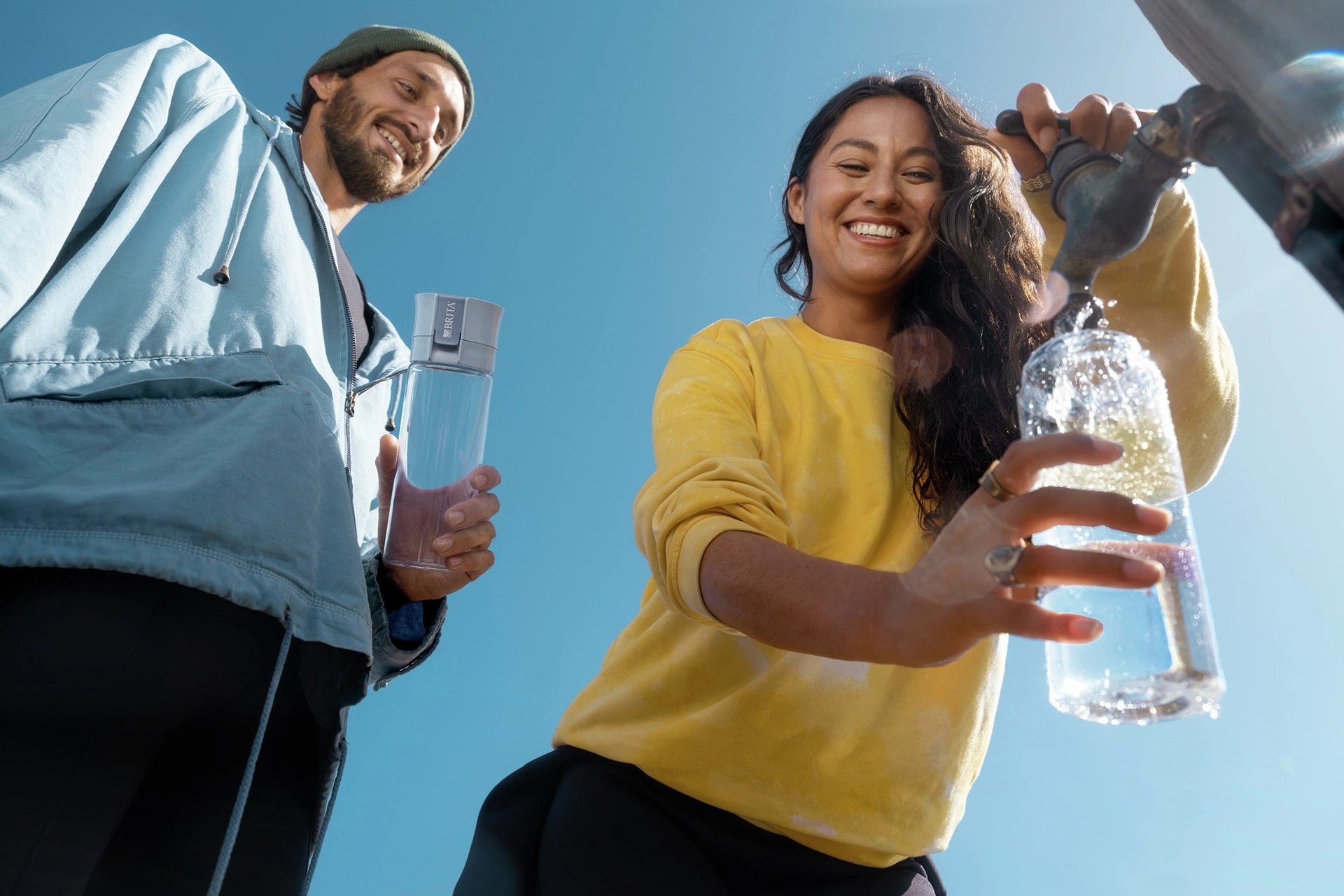 Woman filling her water filter bottle Model Vital outside next to a man.