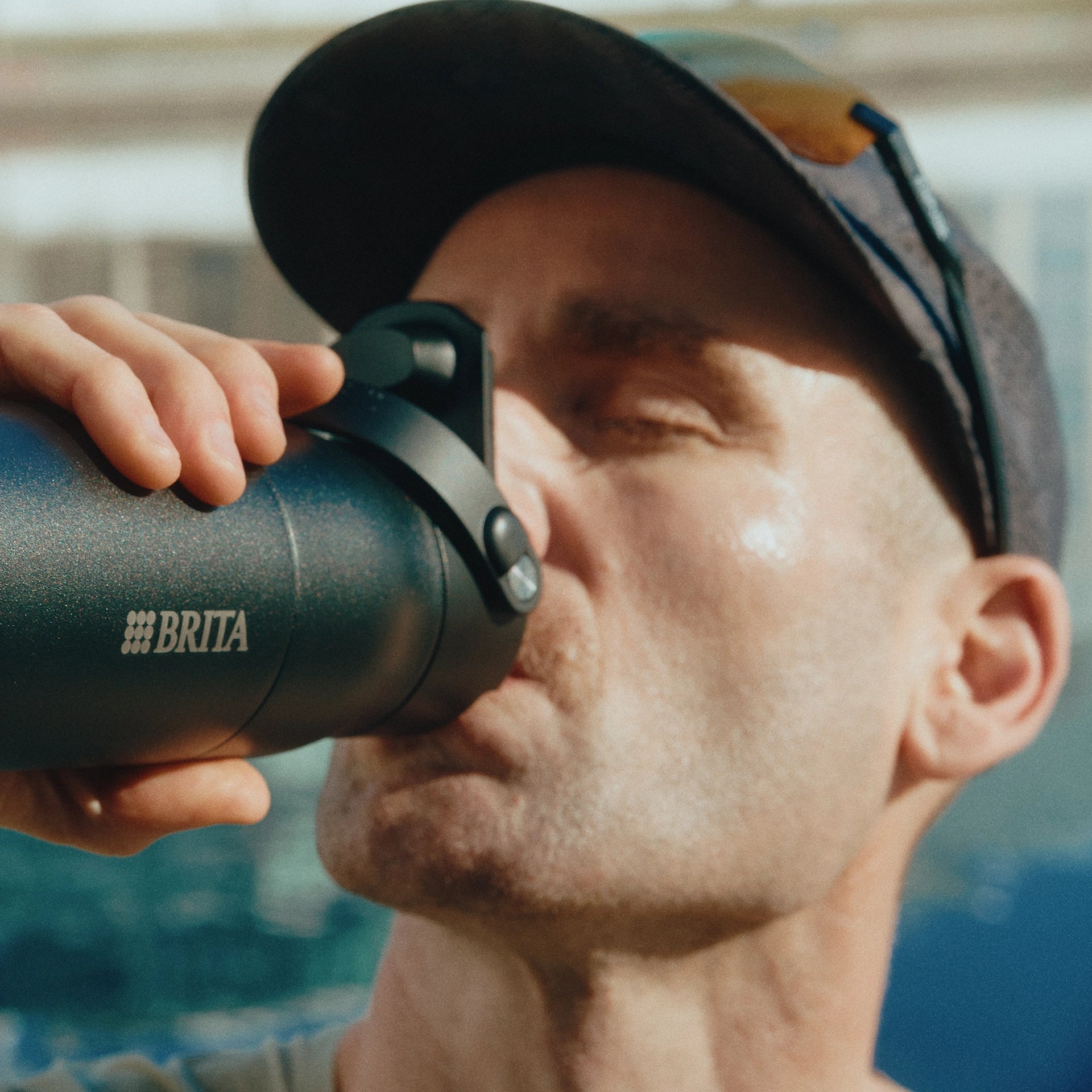 Man drinking from a BRITA water bottle with a scenic background.