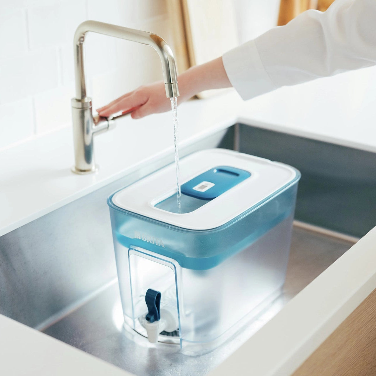 BRITA Flow water filter een bak die in de gootsteen met water wordt gevuld onder een stromende kraan.