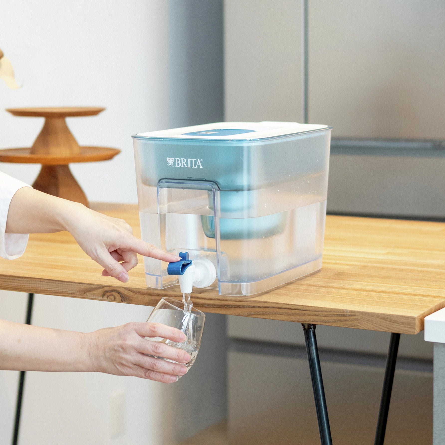 Een BRITA Flow met een MAXTRA PRO PURE PERFORMANCE wordt gebruikt om een glas water te vullen