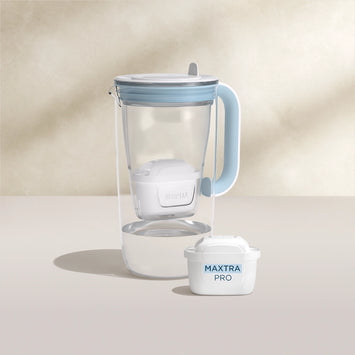 Een water filter Glazen waterfilterkan in blauw op een beige achtergrond