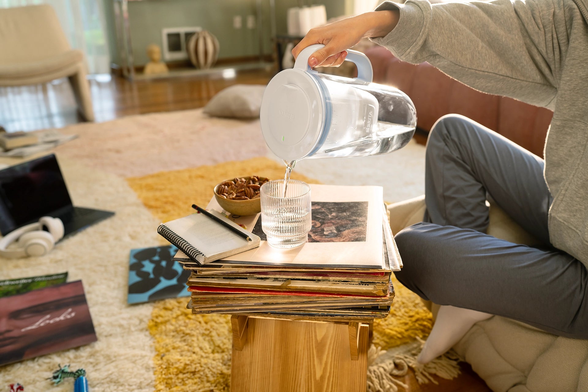 BRITA Glass Jug Blue pouring water into a drinking glass in a living room.