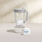 Een water filter Glazen waterfilterkan in grijs op een beige achtergrond