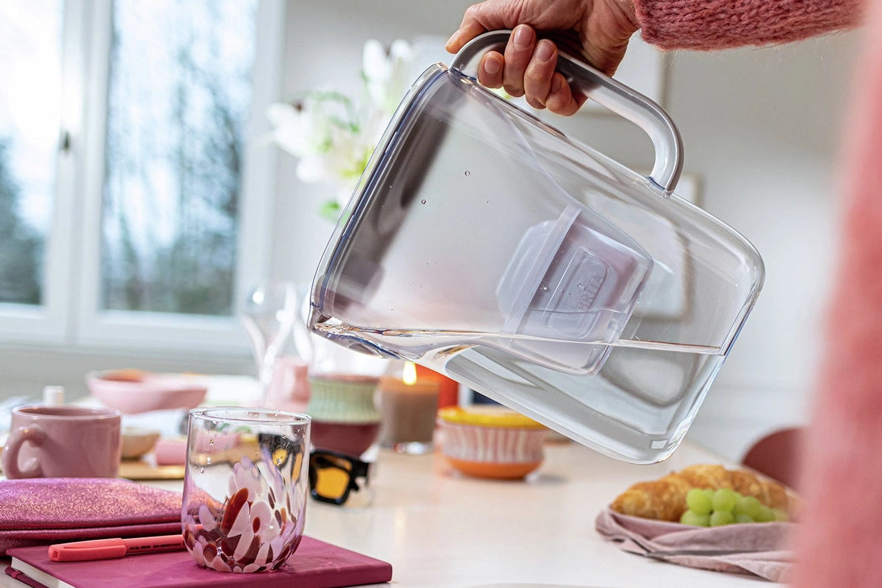 Person in wool cardigan pouring filtered water from the BRITA Style Essential water filter jug