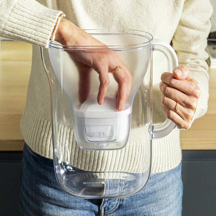 Iemand in een witte trui die een MAXTRA PRO erin stopt filter patroon in een BRITA Style Essential water filter kan.