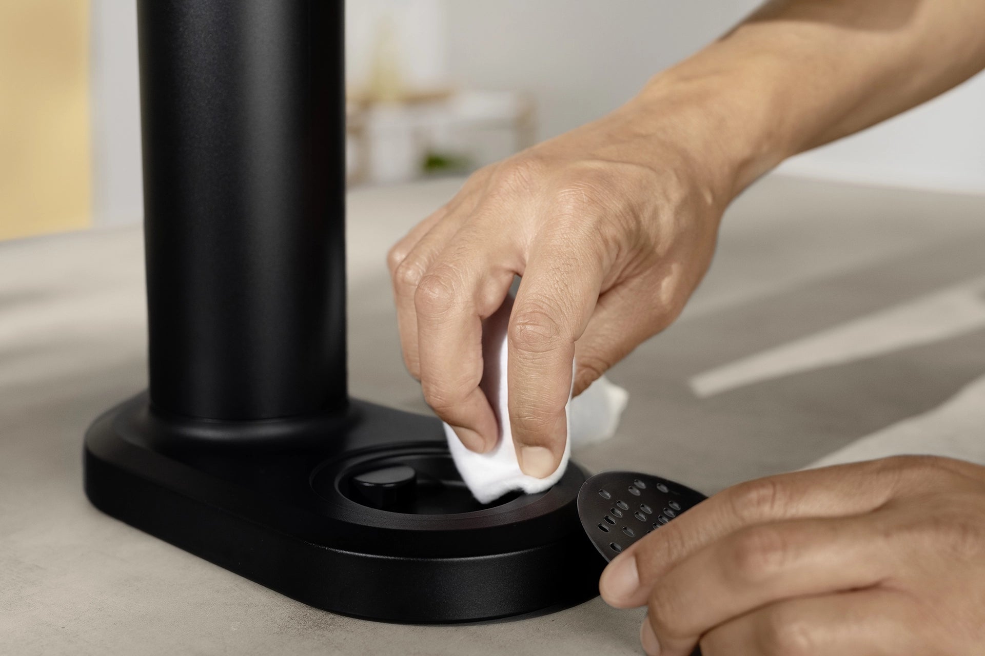 Person cleaning the drip tray of a black BRITA sodaTRIO Sparkling Water Maker.
