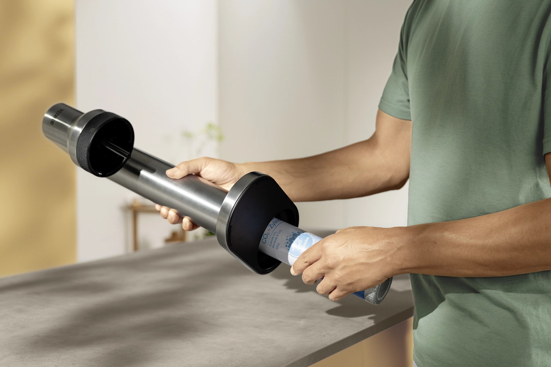 Person inserting a CO₂ cylinder into a BRITA sodaTRIO Pro Sparkling Water Maker.