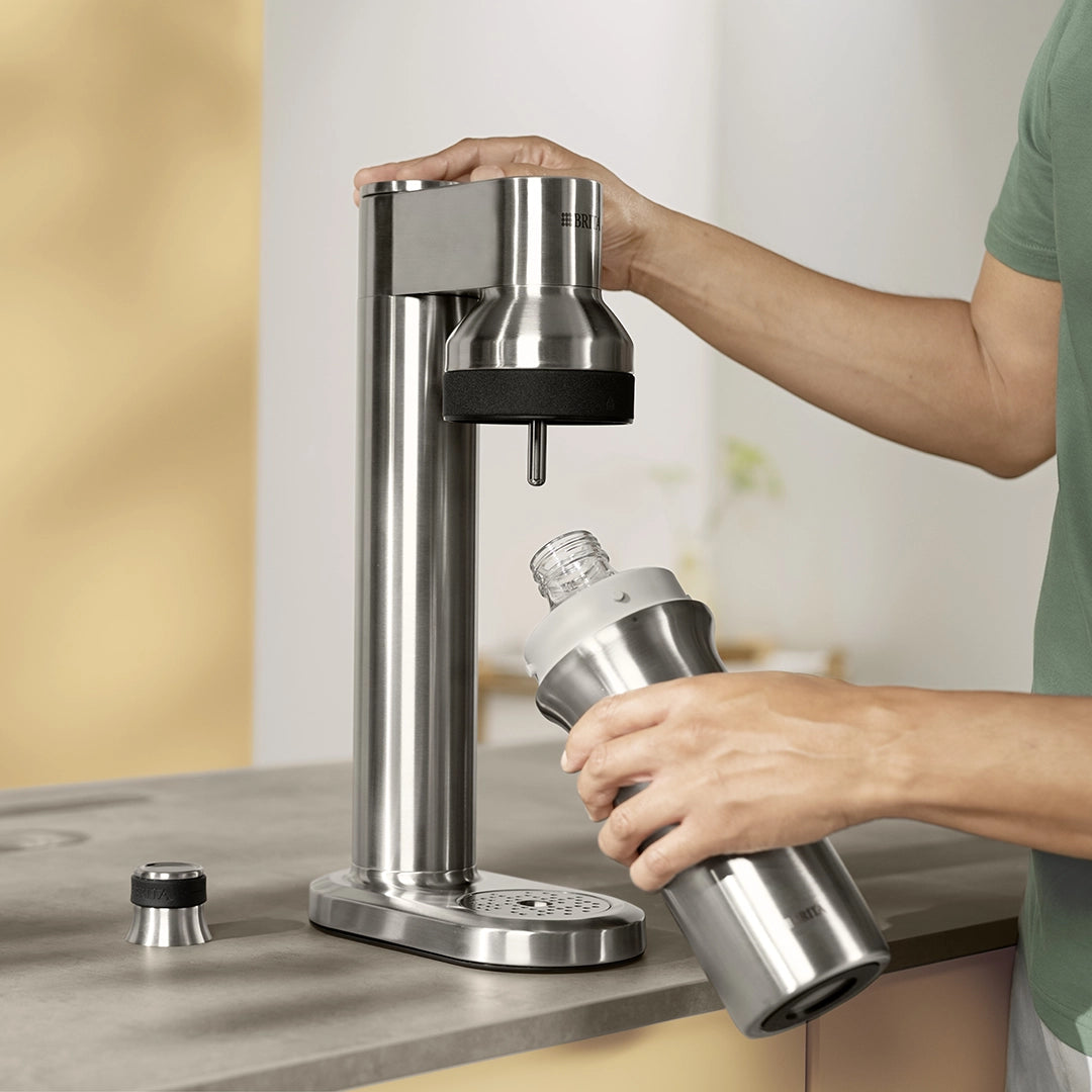 BRITA sodaTRIO Pro sparkling water maker with beverage container being inserted into the carbonation unit