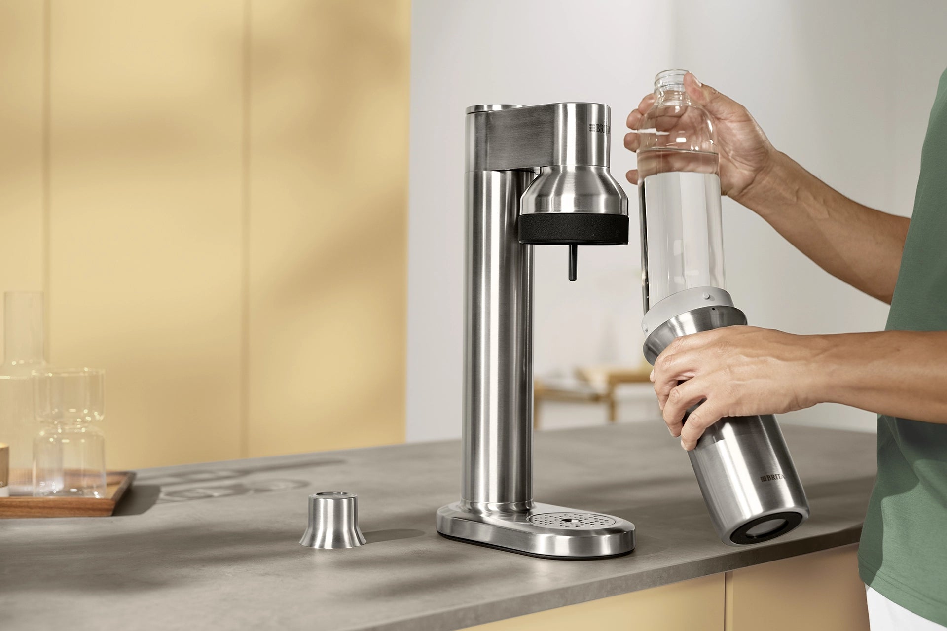 Person inserting a BRITA sodaTRIO Glass Bottle into a BRITA sodaTRIO Pro Sparkling Water Maker.