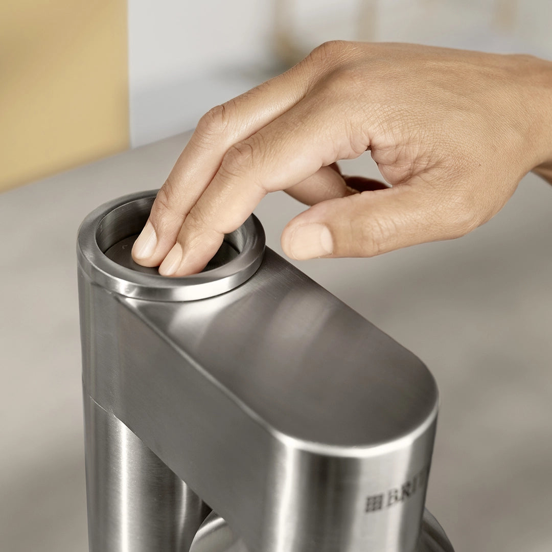 BRITA sodaTRIO Pro sparkling water maker with hand pressing the carbonation button