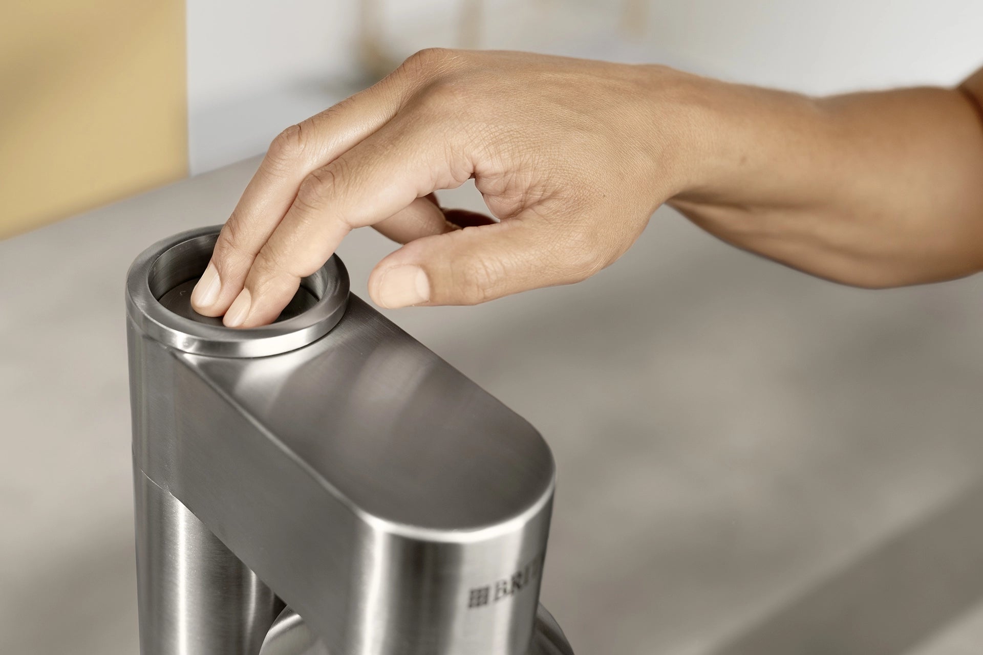 Person pressing the carbonation button on a BRITA sodaTRIO Pro Sparkling Water Maker.