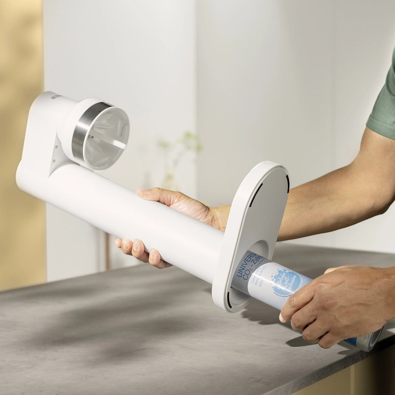 Person inserting a CO₂ cylinder into a white BRITA sodaTRIO Sparkling Water Maker.