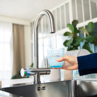 Glass being filled with filtered water from a round BRITA 3-way-tap.